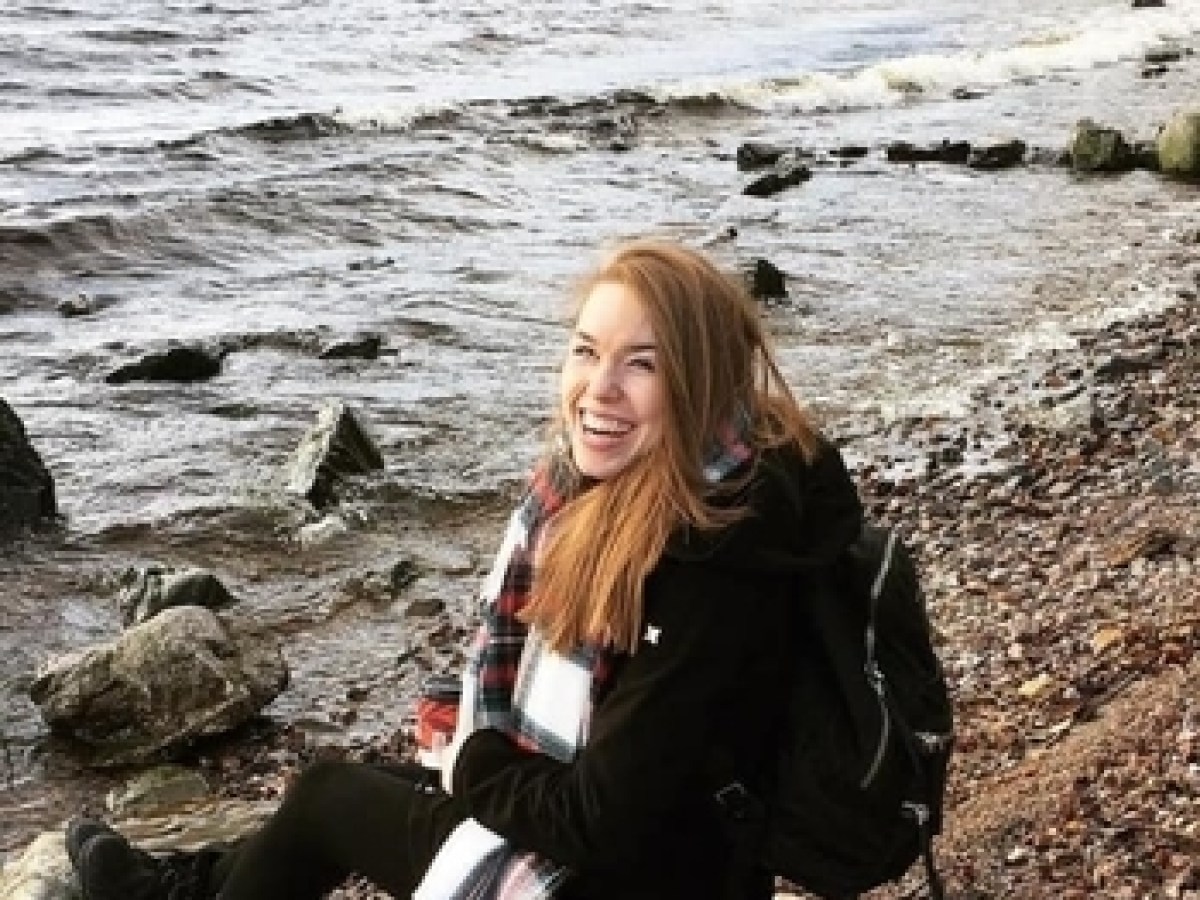 a woman sitting on a rocky beach