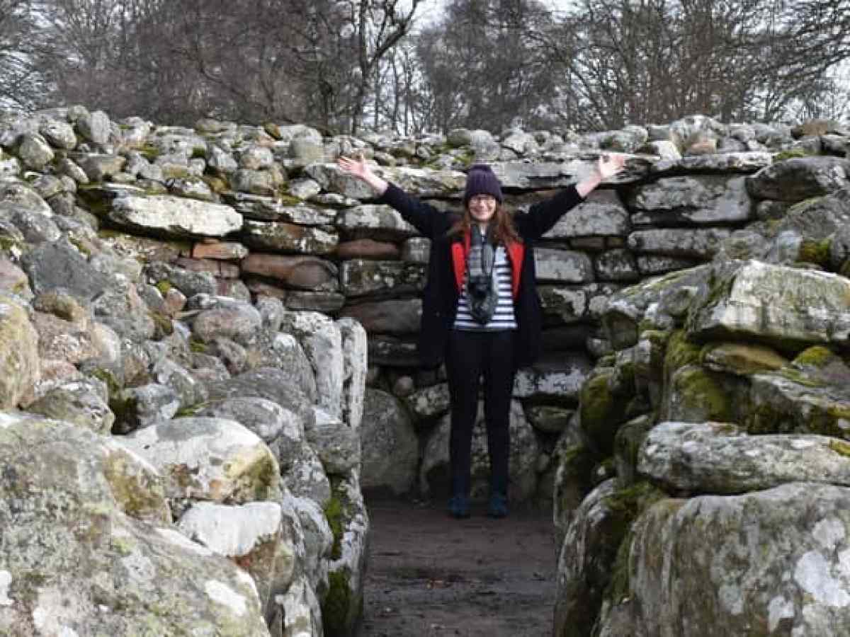 a stone wall in front of a large rock