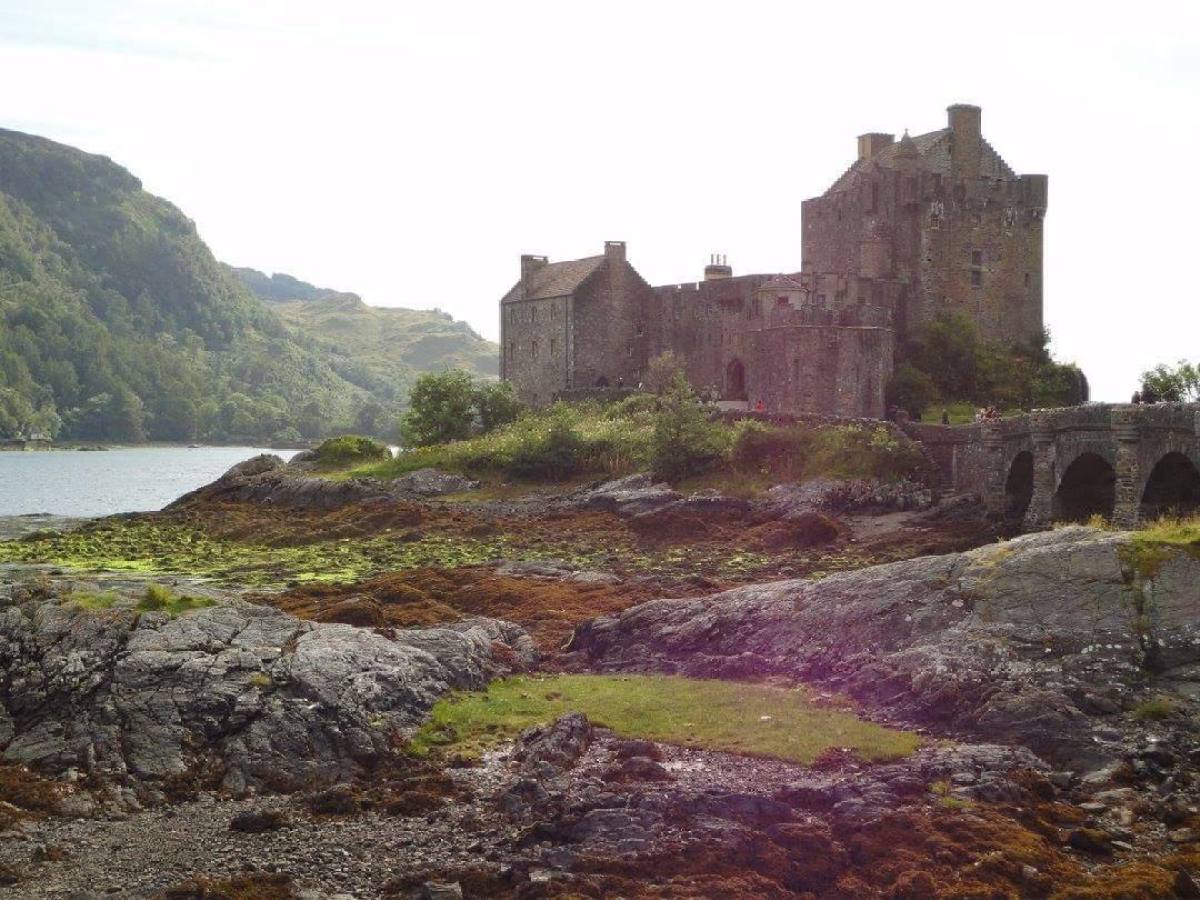a castle on a rocky hill with Eilean Donan in the background