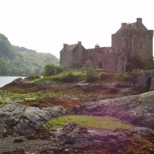 a castle on a rocky hill with Eilean Donan in the background