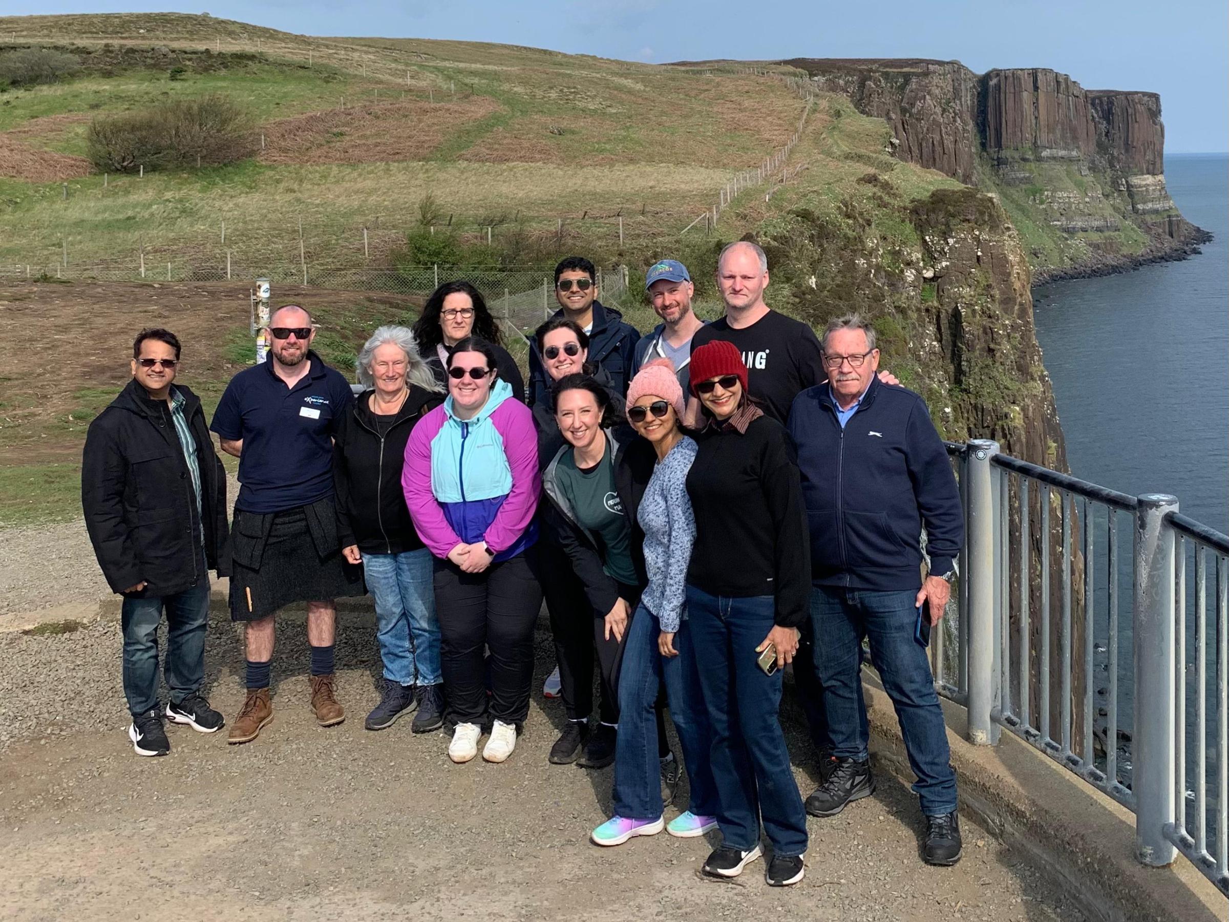 Group of people posing on a coastal cliffside with ocean view.