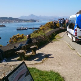 a group of people sitting on a bench next to a body of water