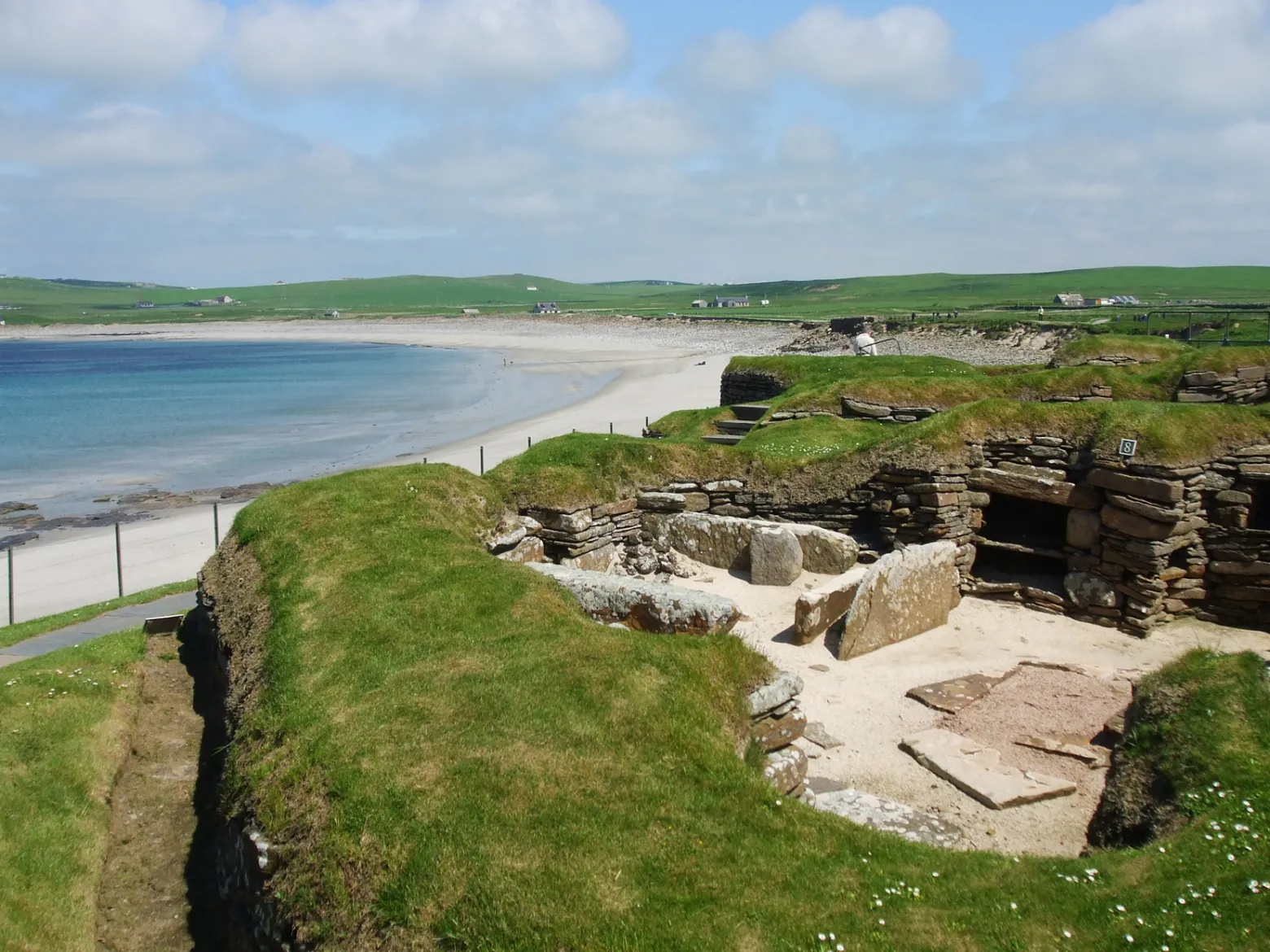an island in the middle of a body of water with Skara Brae in the background