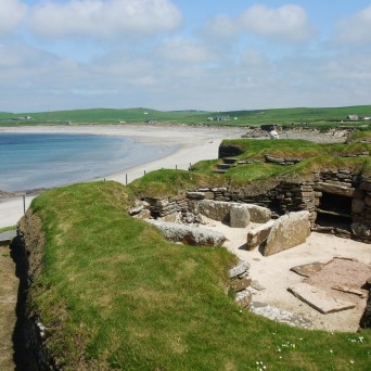 an island in the middle of a body of water with Skara Brae in the background