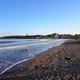 a sandy beach next to a body of water
