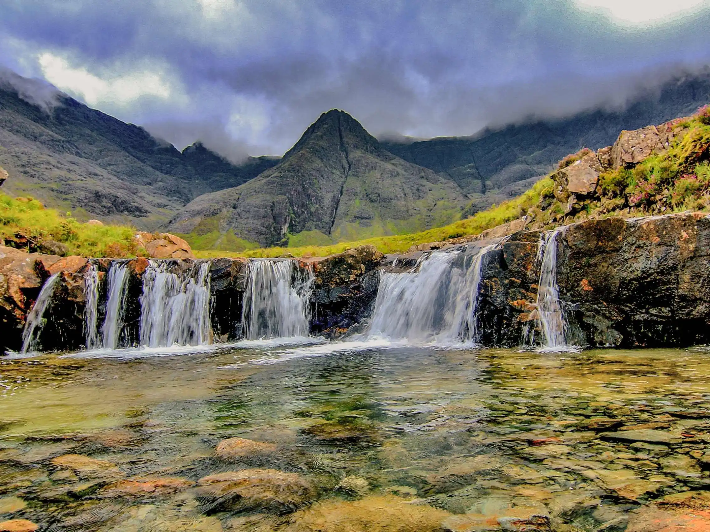 a large waterfall over a body of water with a mountain in the background