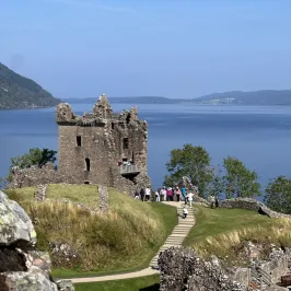 a castle on a hill overlooking a body of water with Urquhart Castle in the background