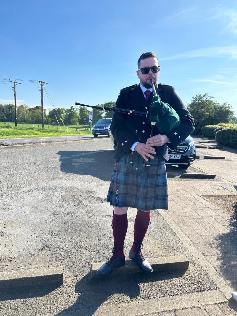 Dejan a man that is standing on the road with a bagpipe