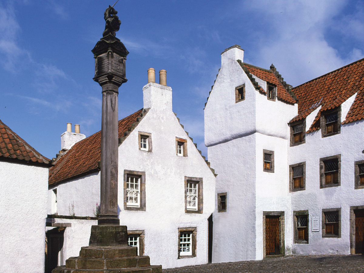Historic European courtyard with white buildings and a stone monument.