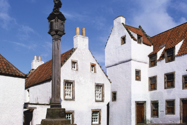 Historic European courtyard with white buildings and a stone monument.