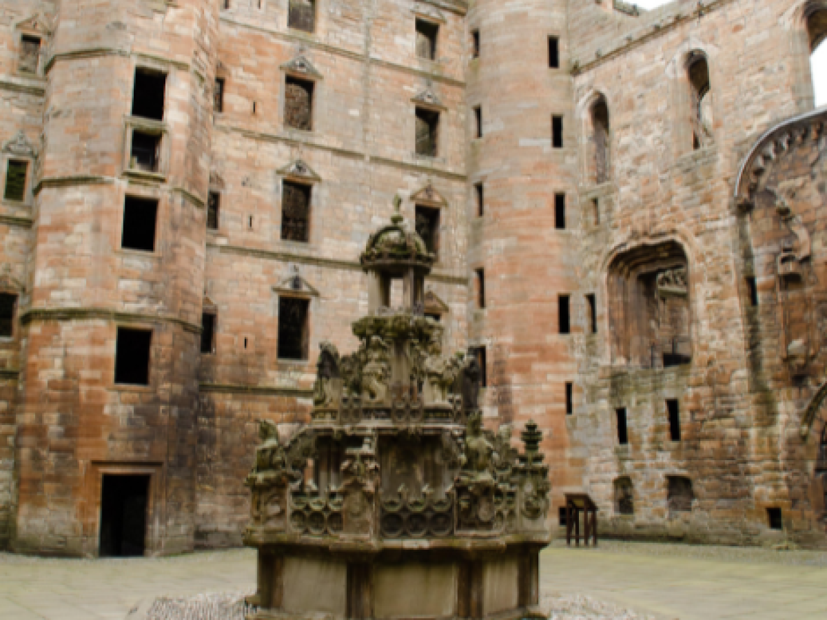 Stone courtyard with ornate fountain and tall brick walls.