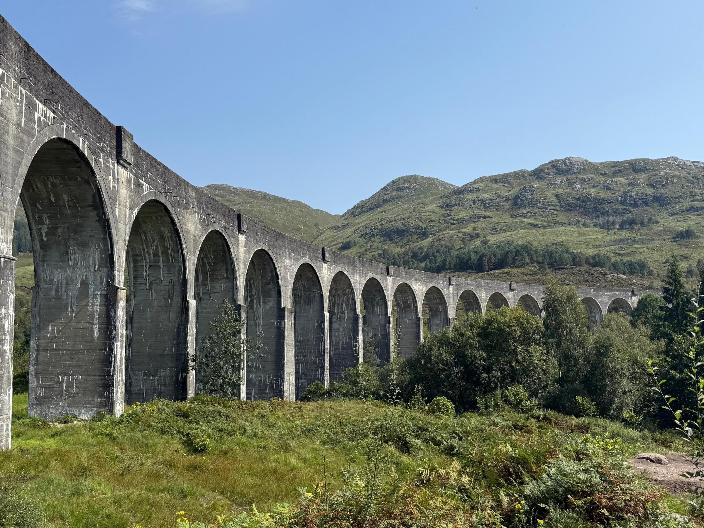 Stone viaduct with multiple arches spanning a lush, green landscape.