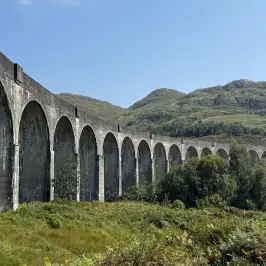 Stone viaduct with multiple arches spanning a lush, green landscape.