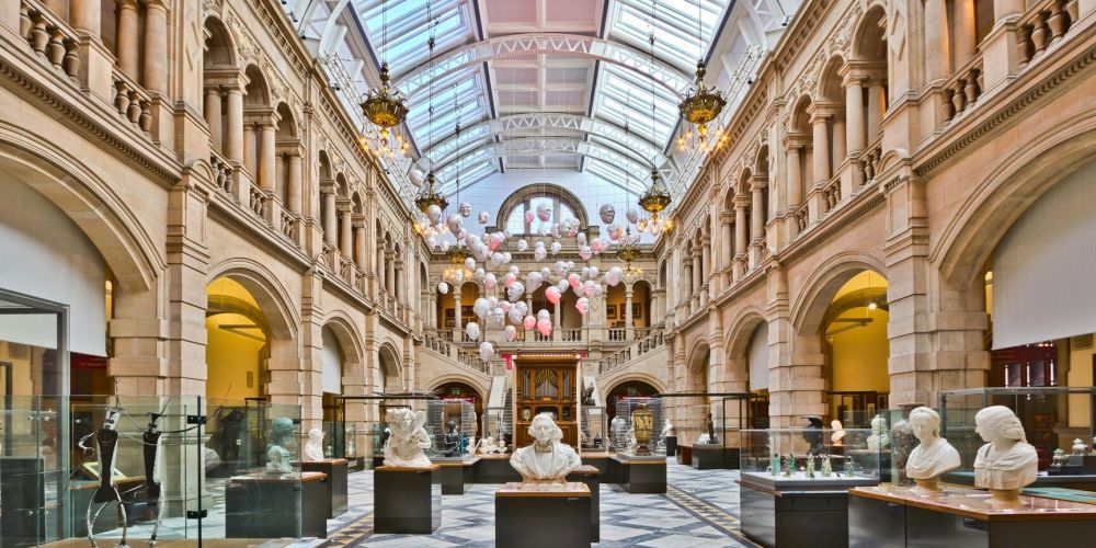 Large hall with sculptures and hanging decorations under a glass ceiling.