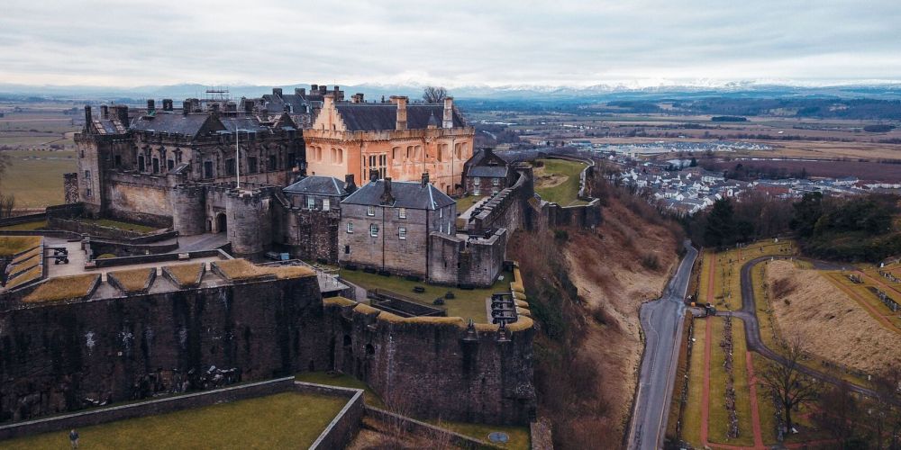 Aerial view of a castle on a hill with surrounding landscape.