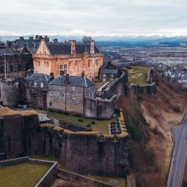 Aerial view of a castle on a hill with surrounding landscape.