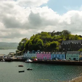 Colorful houses along a waterfront with boats and cloudy sky.